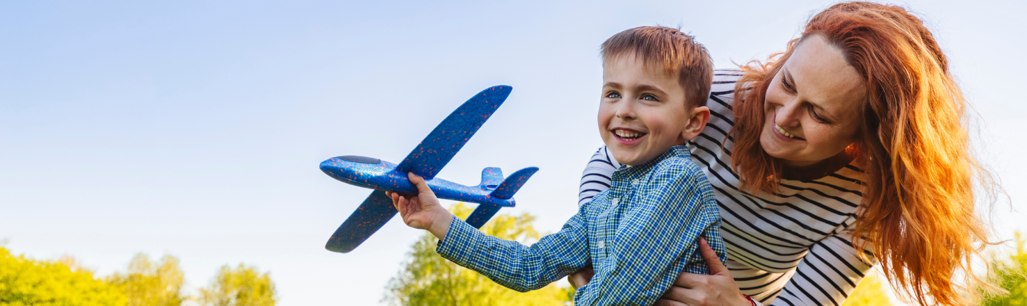 Mom and son playing outside with a toy airplane 